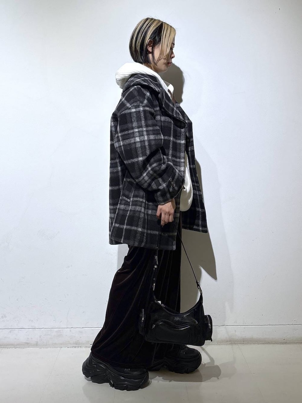 ブラック系のブーツ、ブラック系のチェスターコート、ホワイト系のパーカーを着用したレディースの秋コーディネートの3枚目の写真