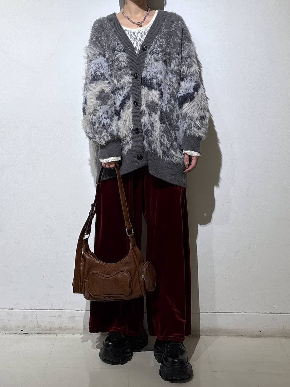 ブラック系のブーツ、ホワイト系のTシャツ/カットソー、グレー系のカーディガン/ボレロを着用したレディースの冬コーディネートの2枚目の写真