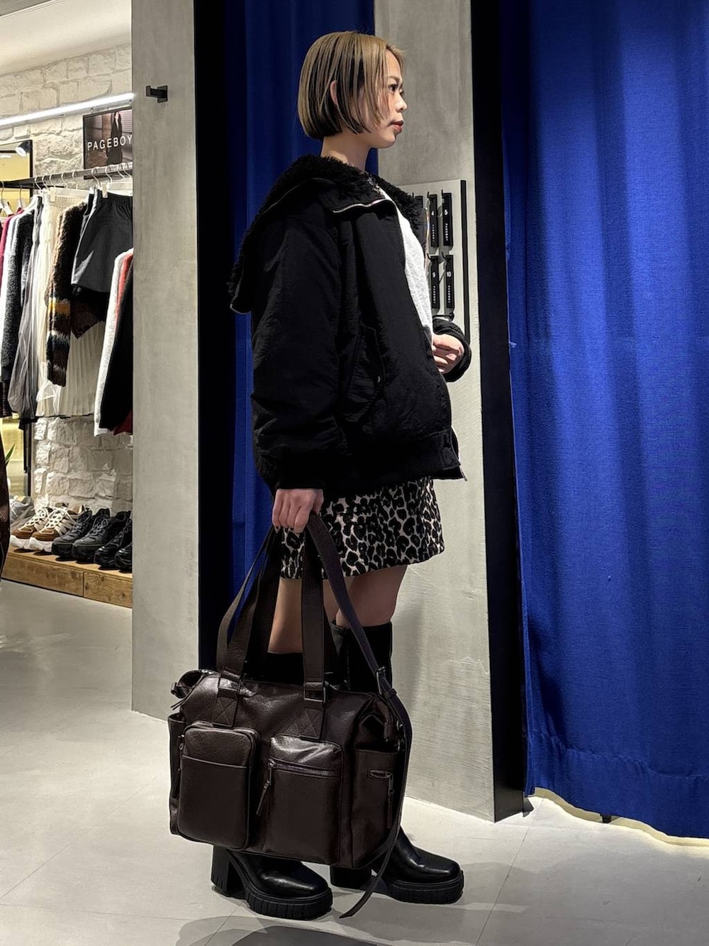 ブラック系のブーツ、ブラウン系のボストンバッグ、ブラック系のブルゾンを着用したレディースの冬コーディネートの3枚目の写真