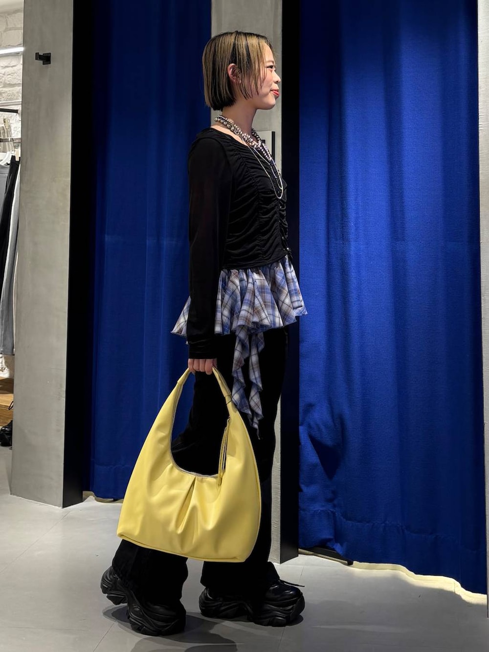 ブラック系のスニーカー、ブラック系のデニムパンツ、イエロー系のトートバッグを着用したレディースの春コーディネートの3枚目の写真