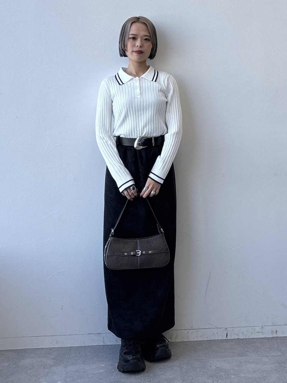 グレー系のスニーカー、ブラック系のスカート、ホワイト系のニット/セーターを着用したレディースの冬コーディネートの2枚目の写真