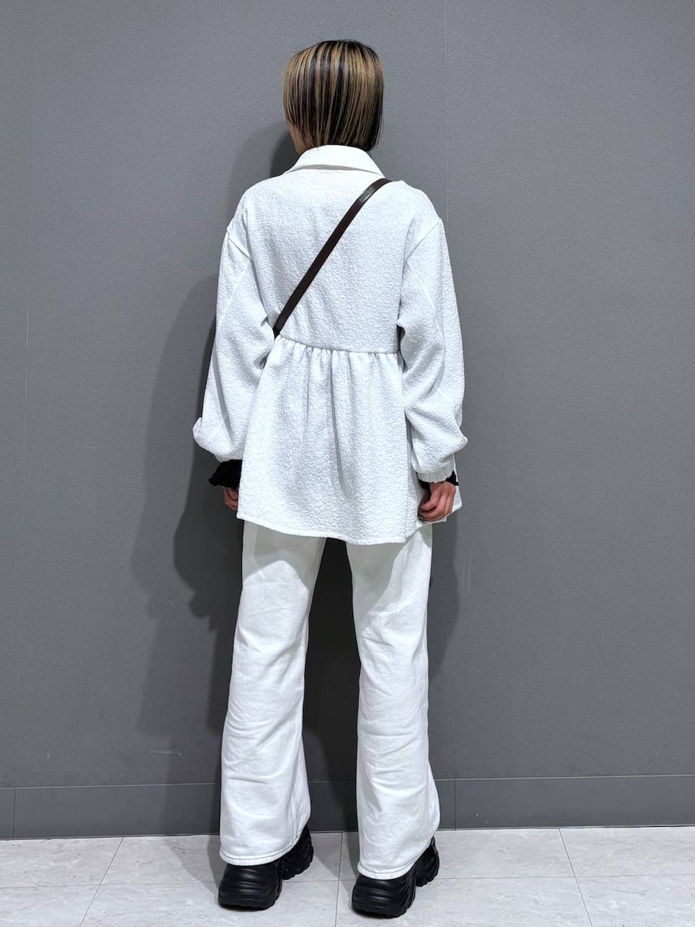 ブラック系のスニーカー、ホワイト系のスラックス、ブラウン系のショルダーバッグを着用したレディースの春コーディネートの5枚目の写真