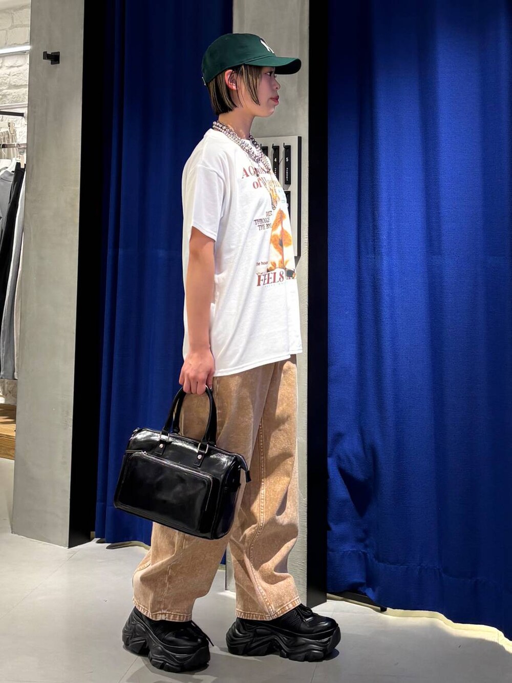 ブラック系のスニーカー、ブラウン系のデニムパンツ、ブラック系のショルダーバッグを着用したレディースの春コーディネートの5枚目の写真