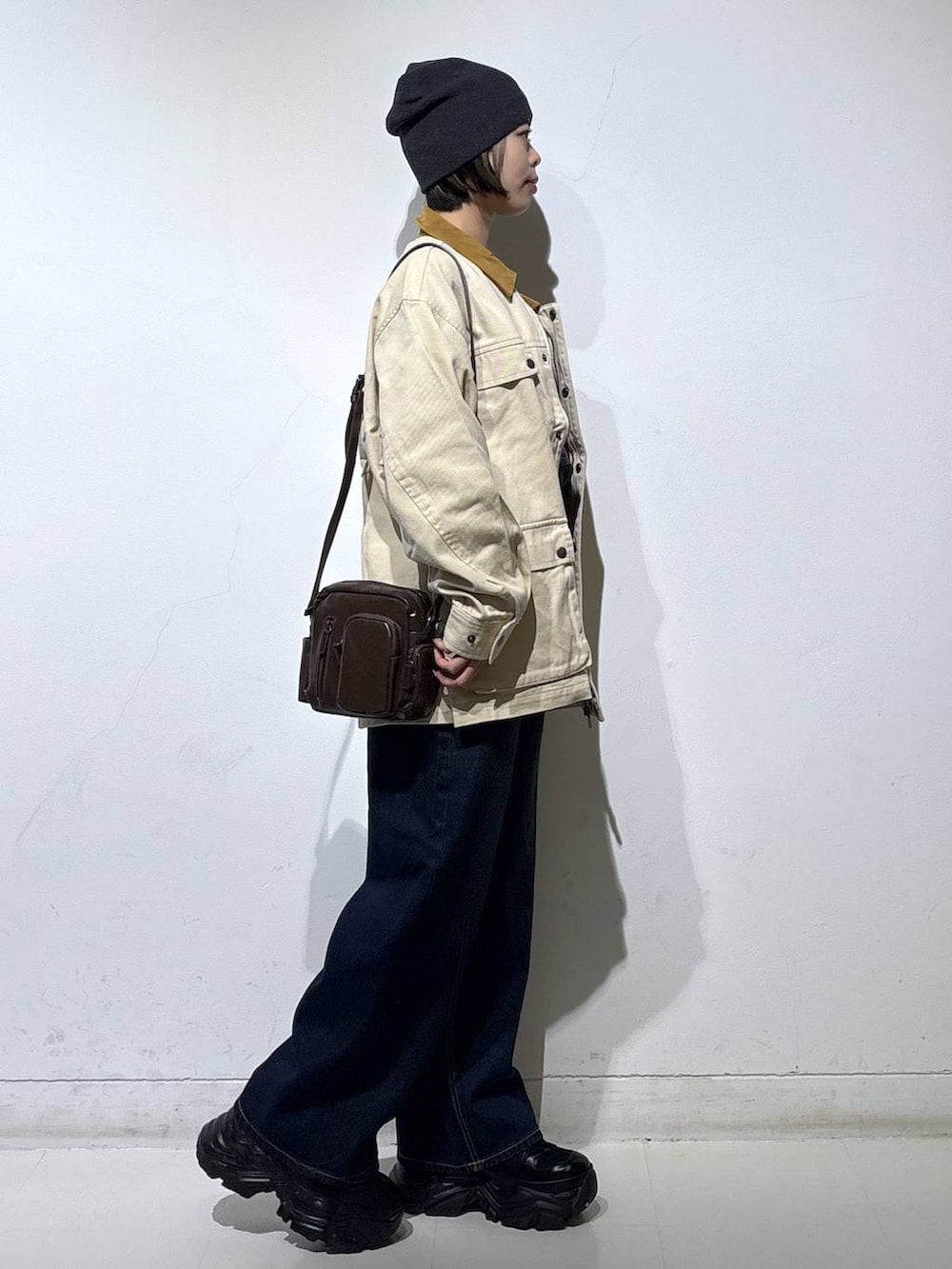 ブラック系のスニーカー、ブルー系のスラックス、ブラウン系のショルダーバッグを着用したレディースの春コーディネートの4枚目の写真