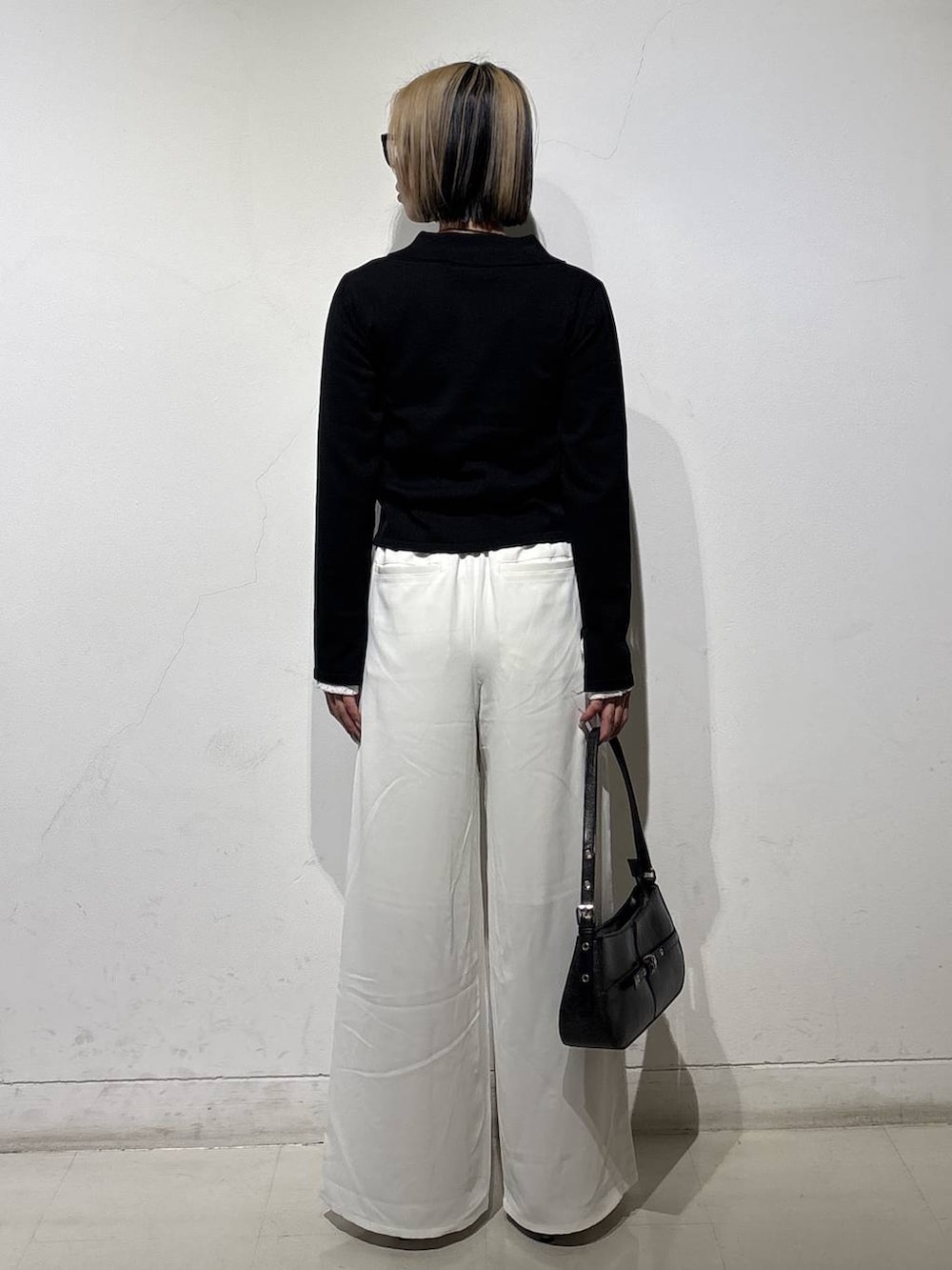 ブラック系のハンドバッグ、ブラウン系のサンダル、ホワイト系のスラックスを着用したレディースの冬コーディネートの4枚目の写真