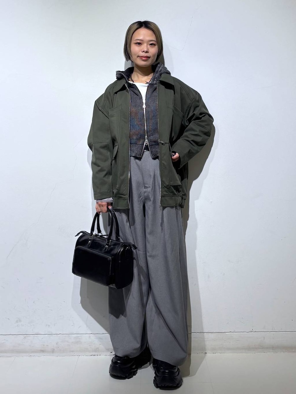 ブラック系のスニーカー、グレー系のパーカー、ブラック系のショルダーバッグを着用したレディースの春コーディネートの2枚目の写真