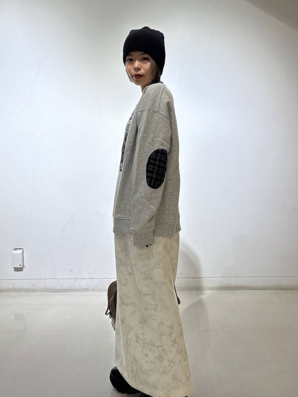 ブラック系のスニーカー、ベージュ系のボストンバッグ、ホワイト系のスカートを着用したレディースの冬コーディネートの6枚目の写真