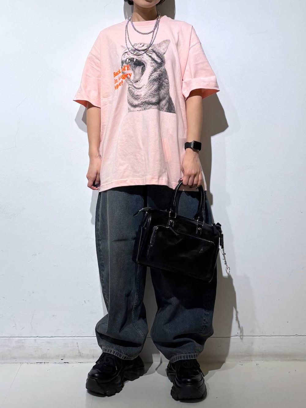 ブラック系のスニーカー、ブルー系のデニムパンツ、ブラック系のショルダーバッグを着用したレディースの春コーディネートの3枚目の写真