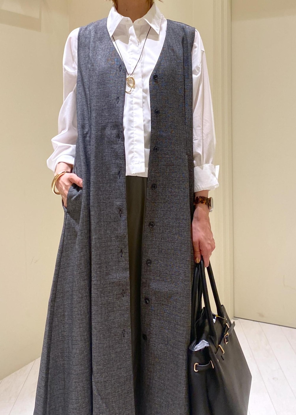 グリーン系のスカート、グレー系のジャンパースカート、ホワイト系のシャツ/ブラウスを着用したレディースの秋コーディネートの5枚目の写真