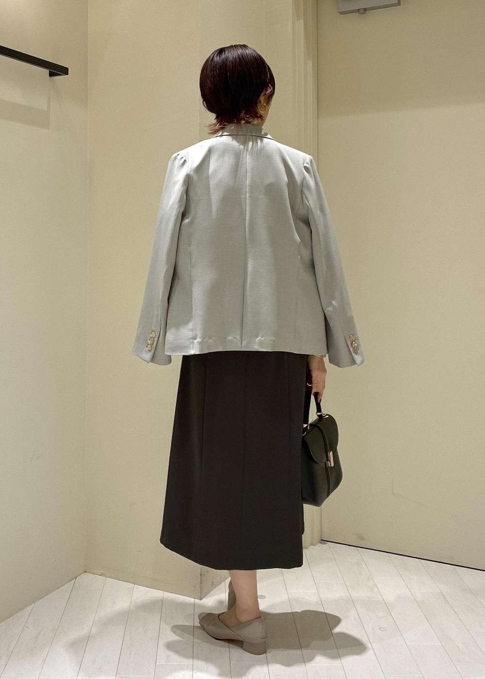 ベージュ系のパンプス、グレー系のドレス、グリーン系のテーラードジャケットを着用したレディースの冬コーディネートの3枚目の写真