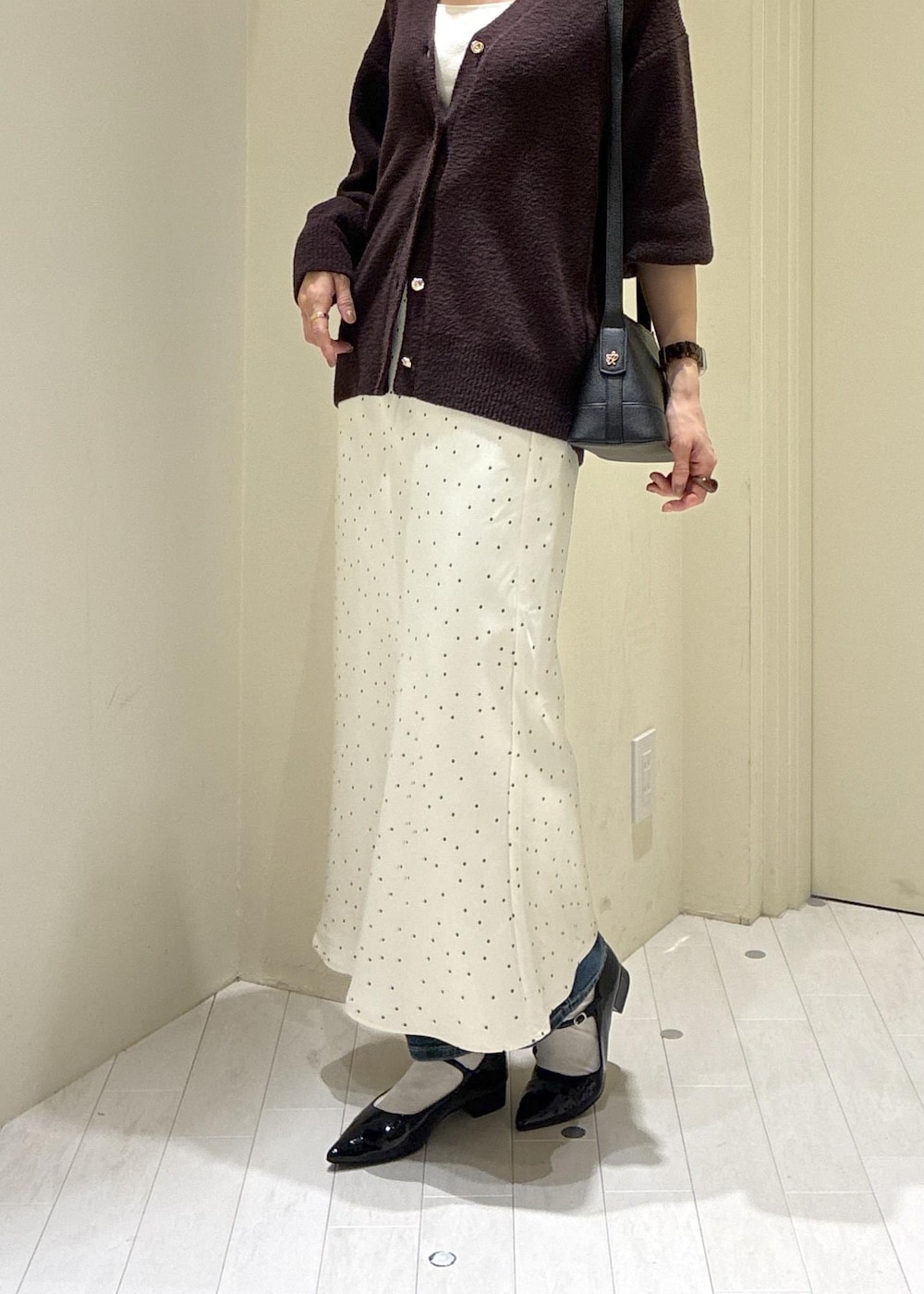 ブルー系のデニムパンツ、ブラック系のパンプス、ブラック系のショルダーバッグを着用したレディースの秋コーディネートの6枚目の写真
