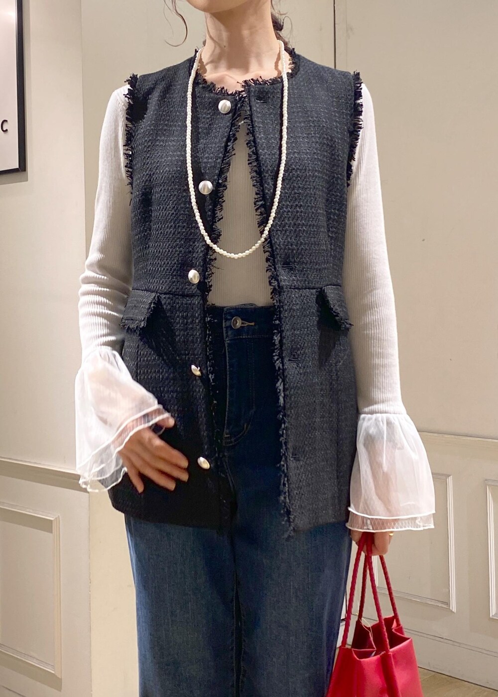ブルー系のデニムパンツ、グレー系のニット/セーター、レッド系のトートバッグを着用したレディースの秋コーディネートの4枚目の写真
