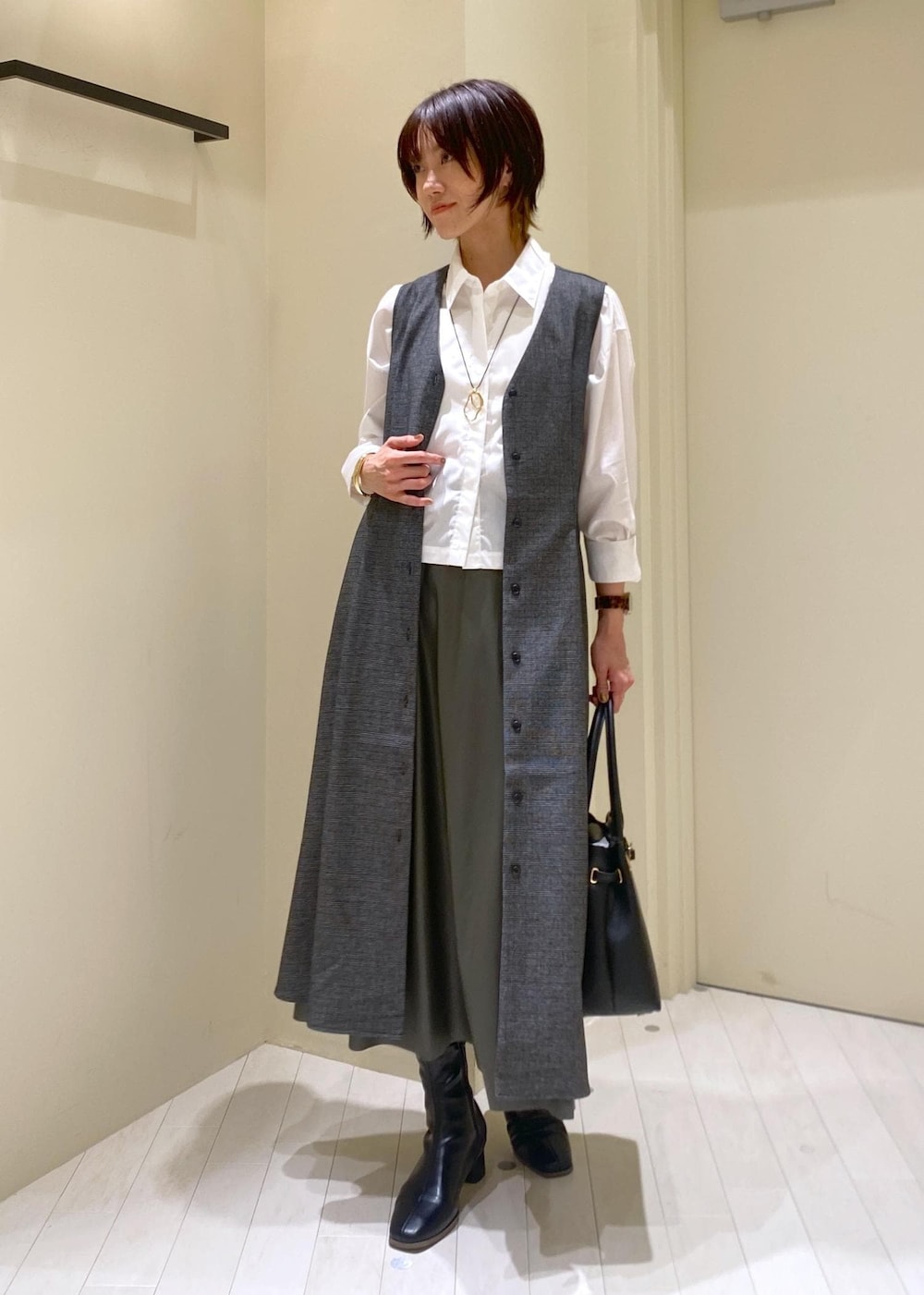 グリーン系のスカート、グレー系のジャンパースカート、ホワイト系のシャツ/ブラウスを着用したレディースの秋コーディネートの2枚目の写真