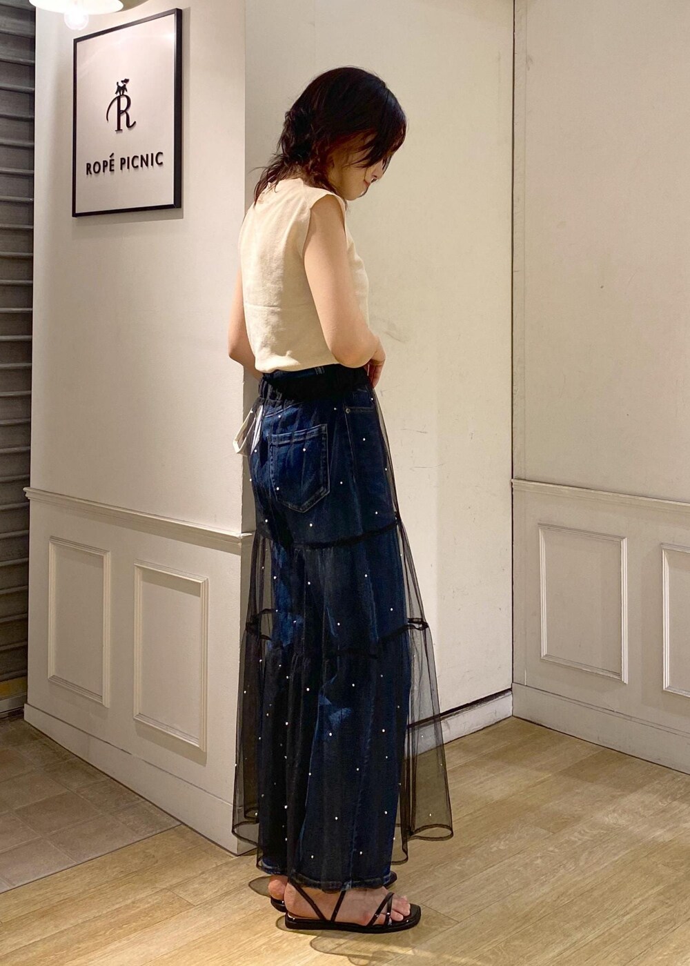 ブラック系のスカート、ブラック系のサンダル、ベージュ系のニット/セーターを着用したレディースの夏コーディネートの3枚目の写真