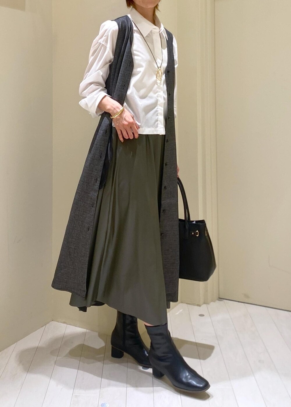 グリーン系のスカート、グレー系のジャンパースカート、ホワイト系のシャツ/ブラウスを着用したレディースの秋コーディネートの3枚目の写真