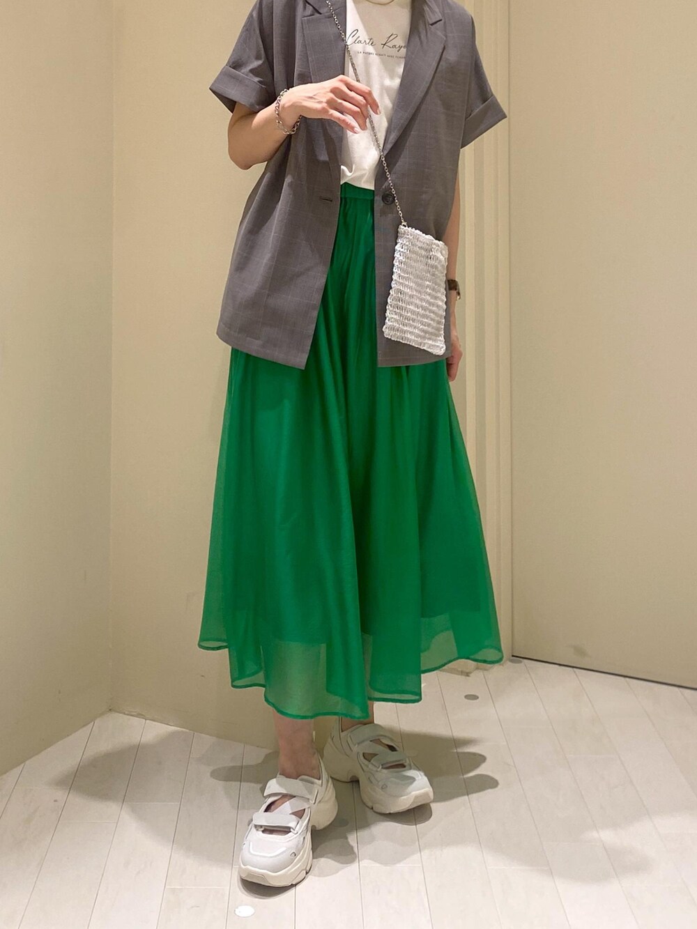 グリーン系のスカート、ホワイト系のTシャツ/カットソー、グレー系のテーラードジャケットを着用したレディースの夏コーディネートの6枚目の写真