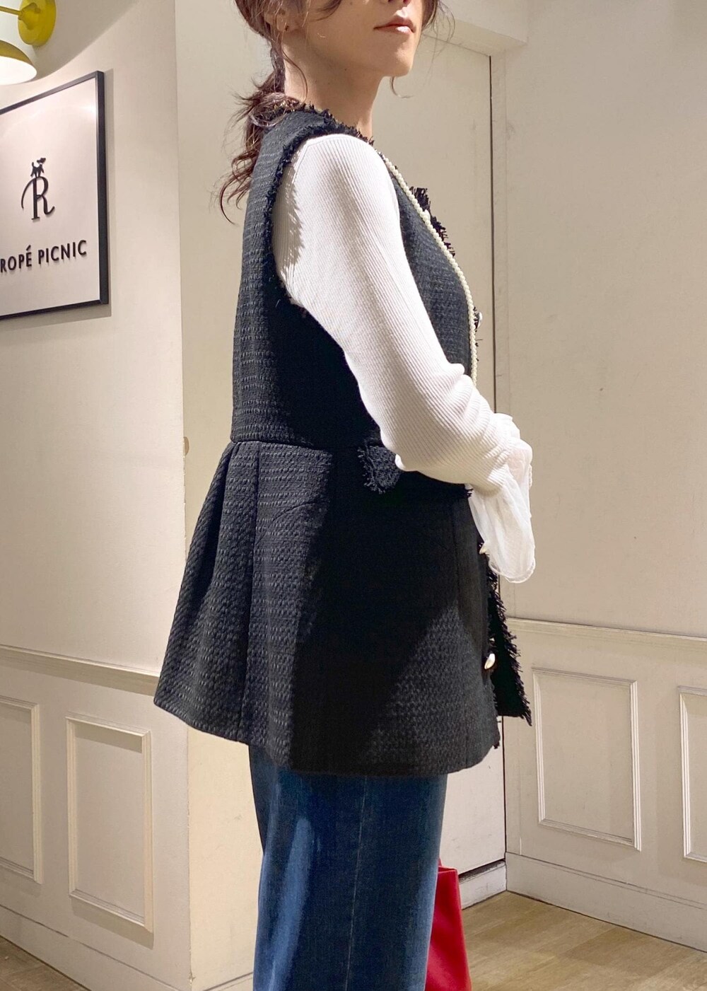 ブルー系のデニムパンツ、グレー系のニット/セーター、レッド系のトートバッグを着用したレディースの秋コーディネートの5枚目の写真