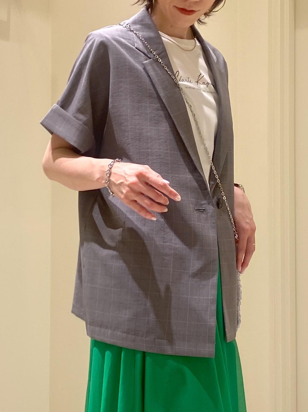 グリーン系のスカート、ホワイト系のTシャツ/カットソー、グレー系のテーラードジャケットを着用したレディースの夏コーディネートの4枚目の写真