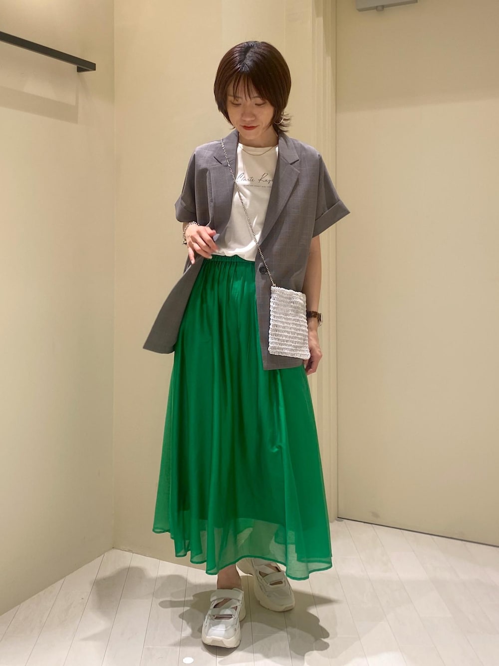グリーン系のスカート、ホワイト系のTシャツ/カットソー、グレー系のテーラードジャケットを着用したレディースの夏コーディネートの8枚目の写真