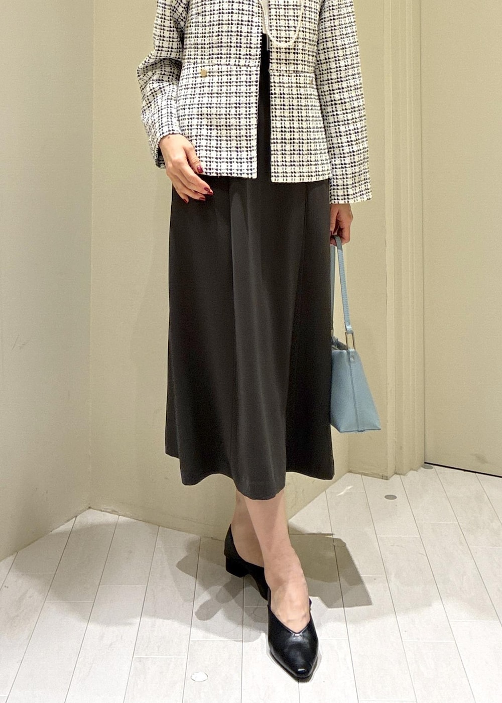 ブラック系のパンプス、ブルー系のショルダーバッグ、グレー系のドレスを着用したレディースの冬コーディネートの3枚目の写真