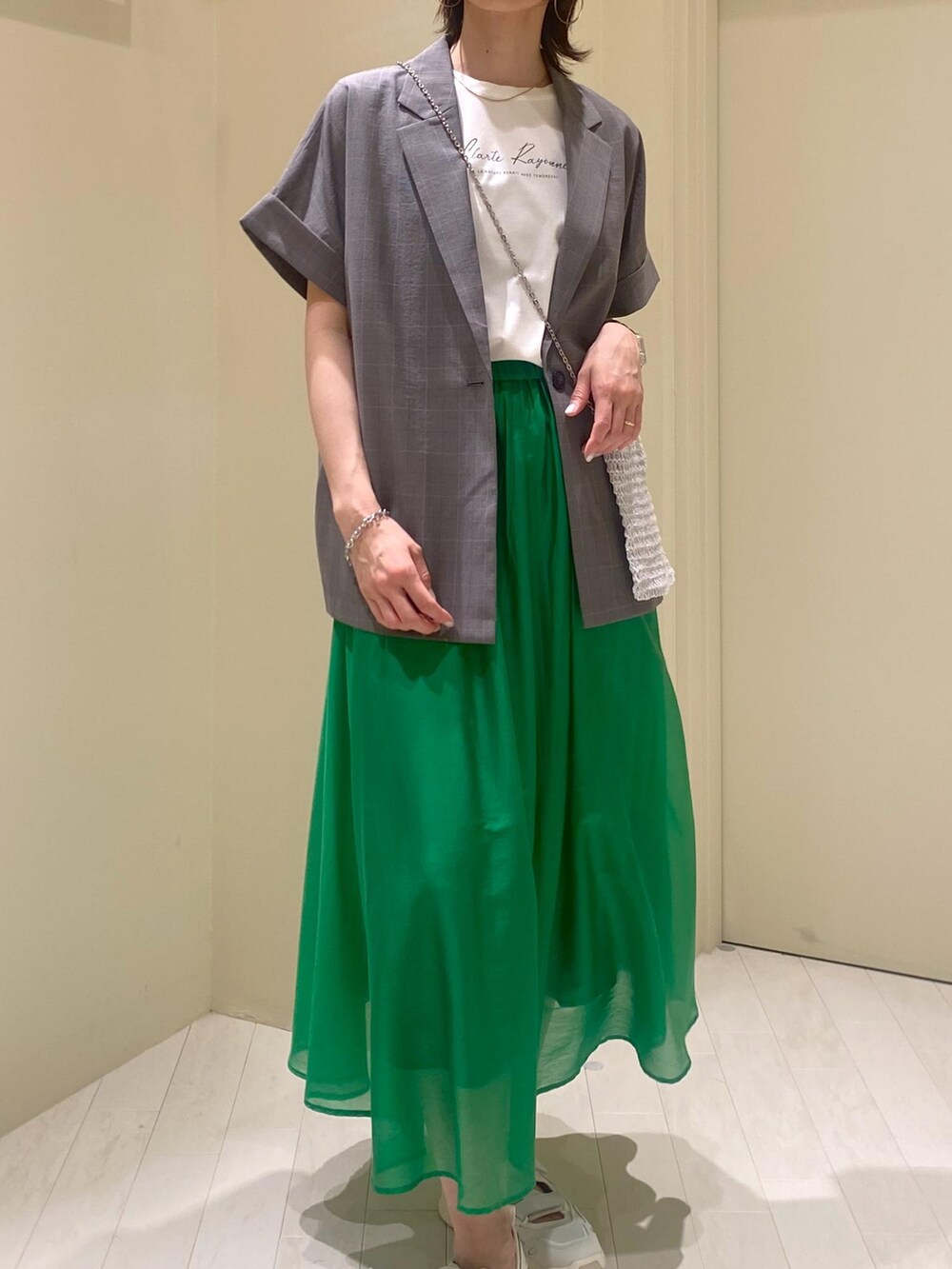 グリーン系のスカート、ホワイト系のTシャツ/カットソー、グレー系のテーラードジャケットを着用したレディースの夏コーディネートの5枚目の写真