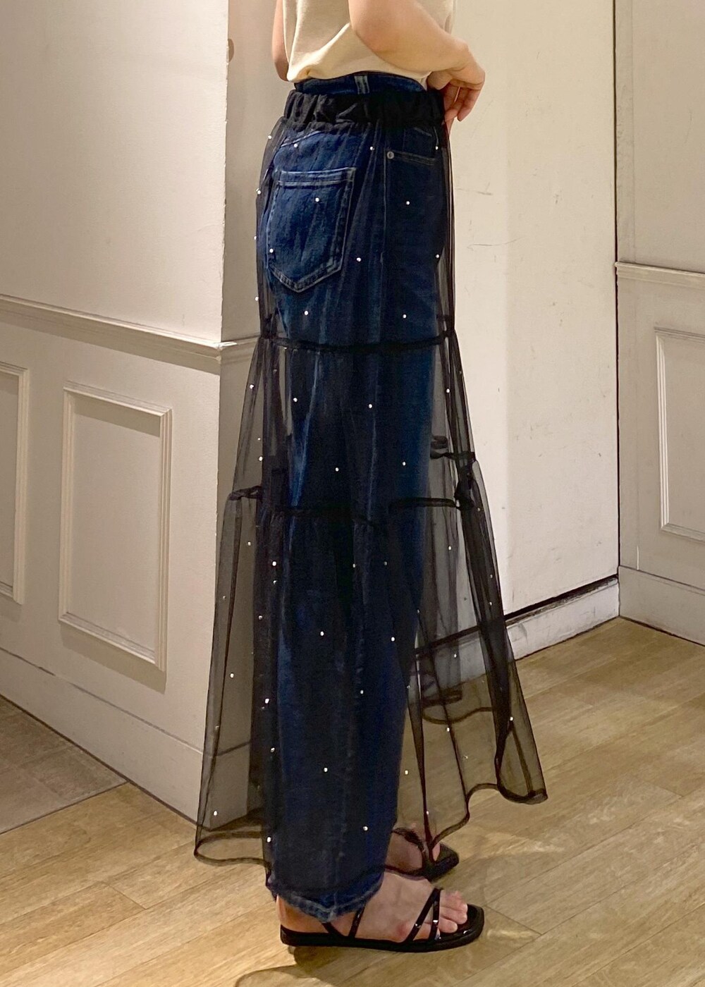 ブラック系のスカート、ブラック系のサンダル、ベージュ系のニット/セーターを着用したレディースの夏コーディネートの4枚目の写真