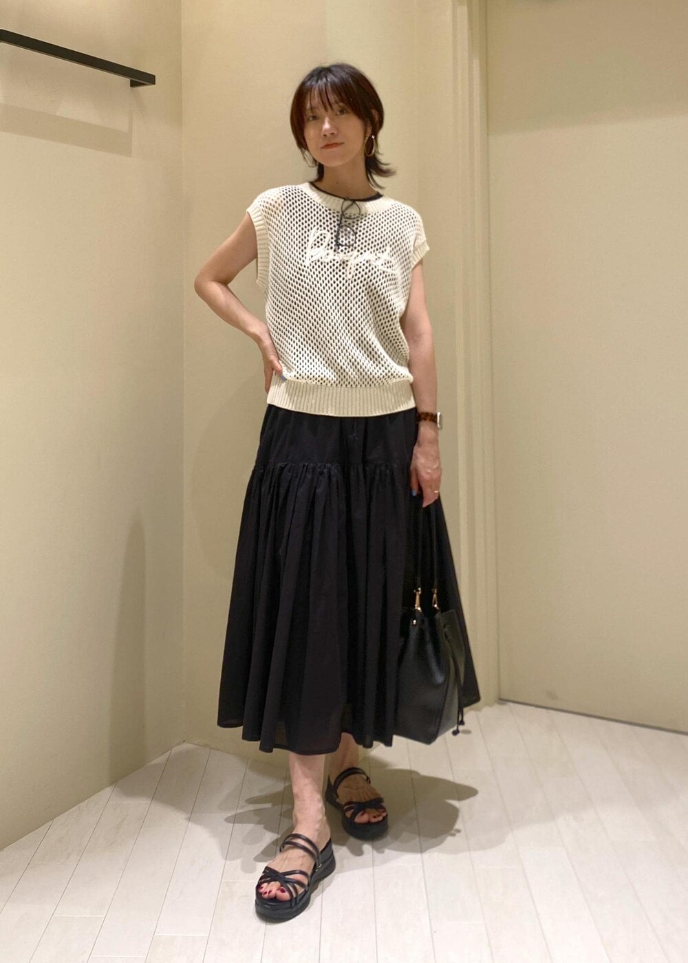 ブラック系のワンピース、ホワイト系のニット/セーター、ブラック系のショルダーバッグを着用したレディースの夏コーディネートの2枚目の写真