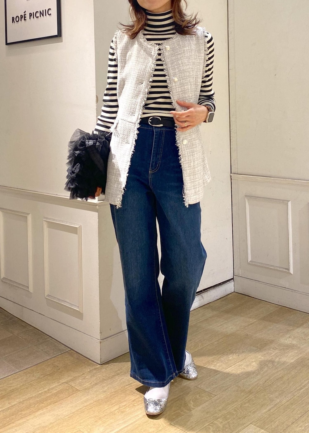 ブルー系のデニムパンツ、ブラック系のベスト、シルバー系のバレエシューズを着用したレディースの冬コーディネートの4枚目の写真