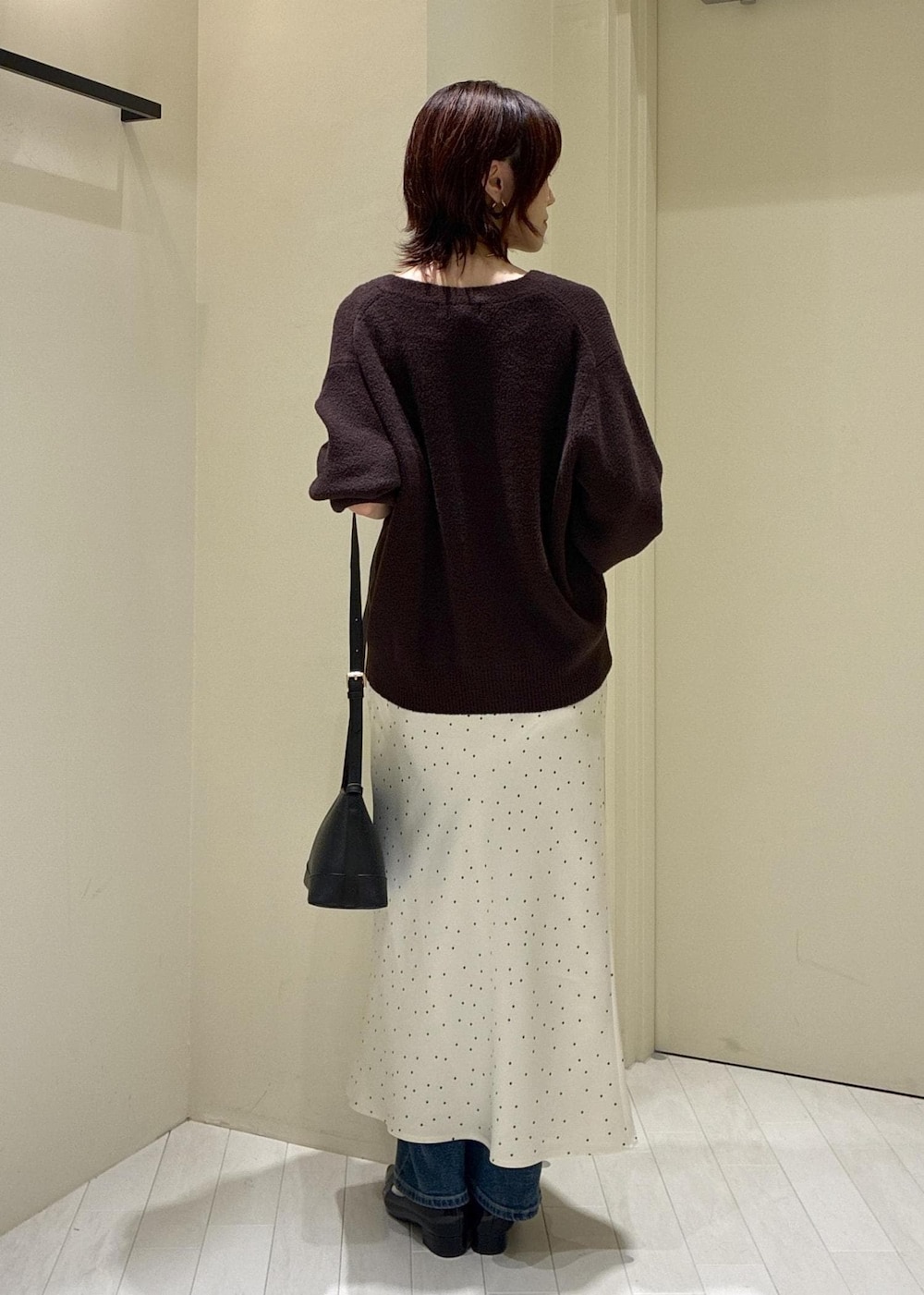 ブルー系のデニムパンツ、ブラック系のパンプス、ブラック系のショルダーバッグを着用したレディースの秋コーディネートの2枚目の写真
