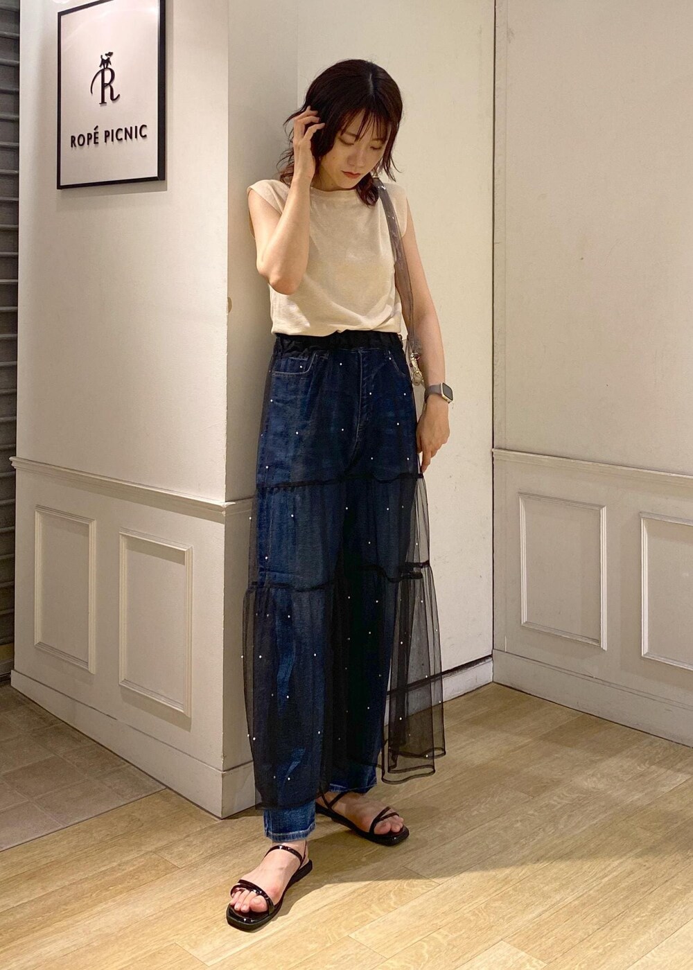 ブラック系のスカート、ブラック系のサンダル、ベージュ系のニット/セーターを着用したレディースの夏コーディネートの2枚目の写真