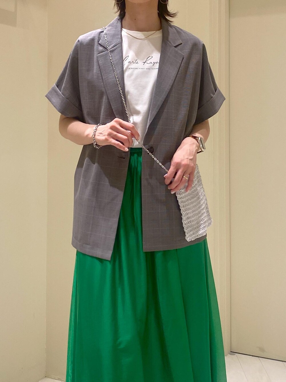 グリーン系のスカート、ホワイト系のTシャツ/カットソー、グレー系のテーラードジャケットを着用したレディースの夏コーディネートの3枚目の写真