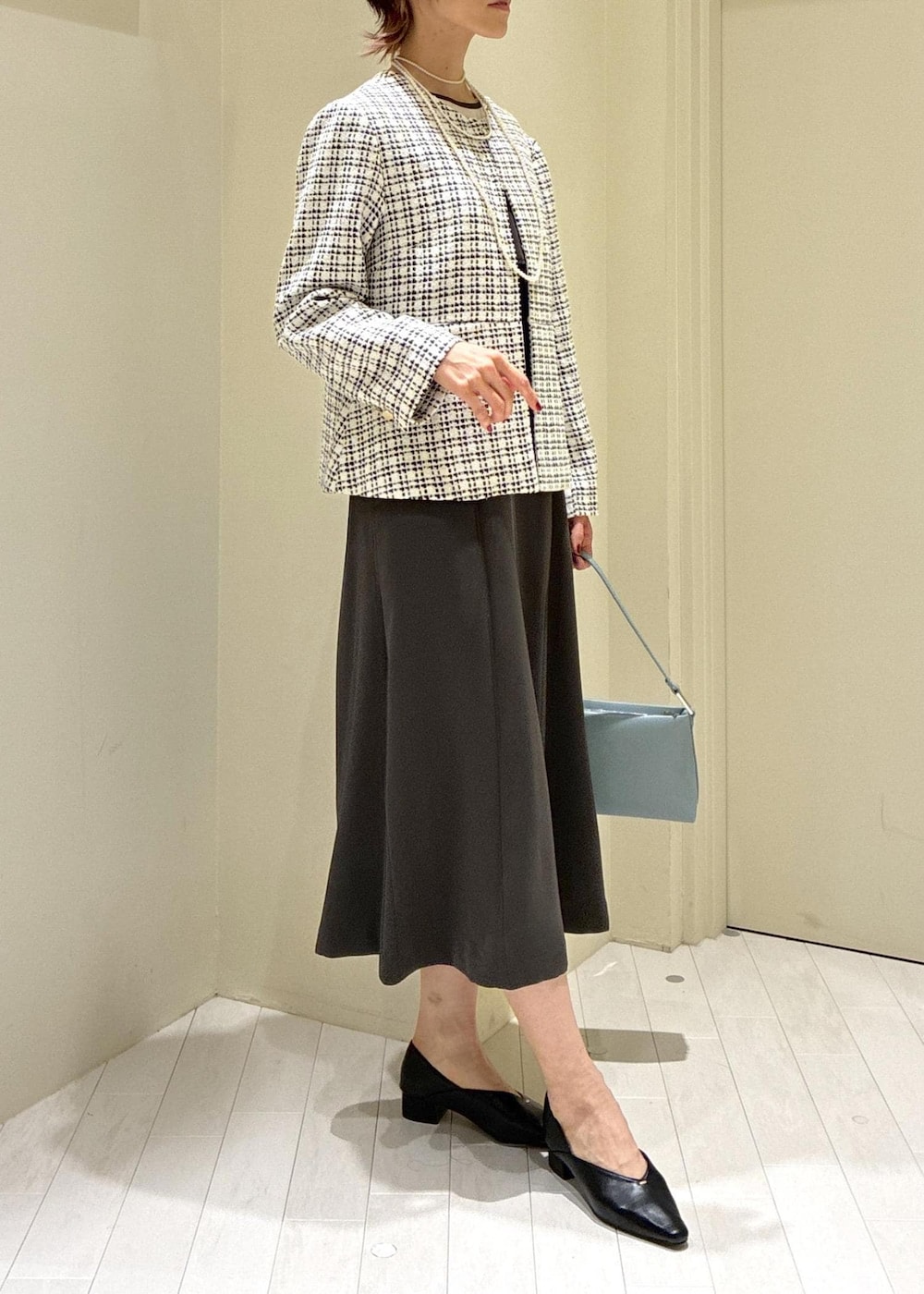 ブラック系のパンプス、ブルー系のショルダーバッグ、グレー系のドレスを着用したレディースの冬コーディネートの2枚目の写真