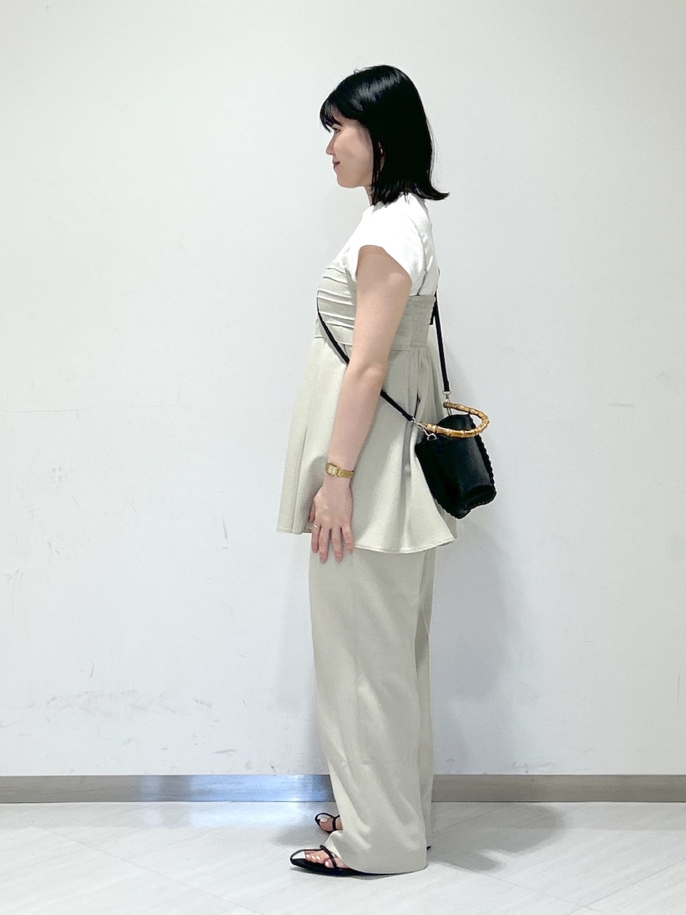 ベージュ系のスラックス、ブラック系のサンダル、ベージュ系のキャミソールを着用したレディースの夏コーディネートの2枚目の写真