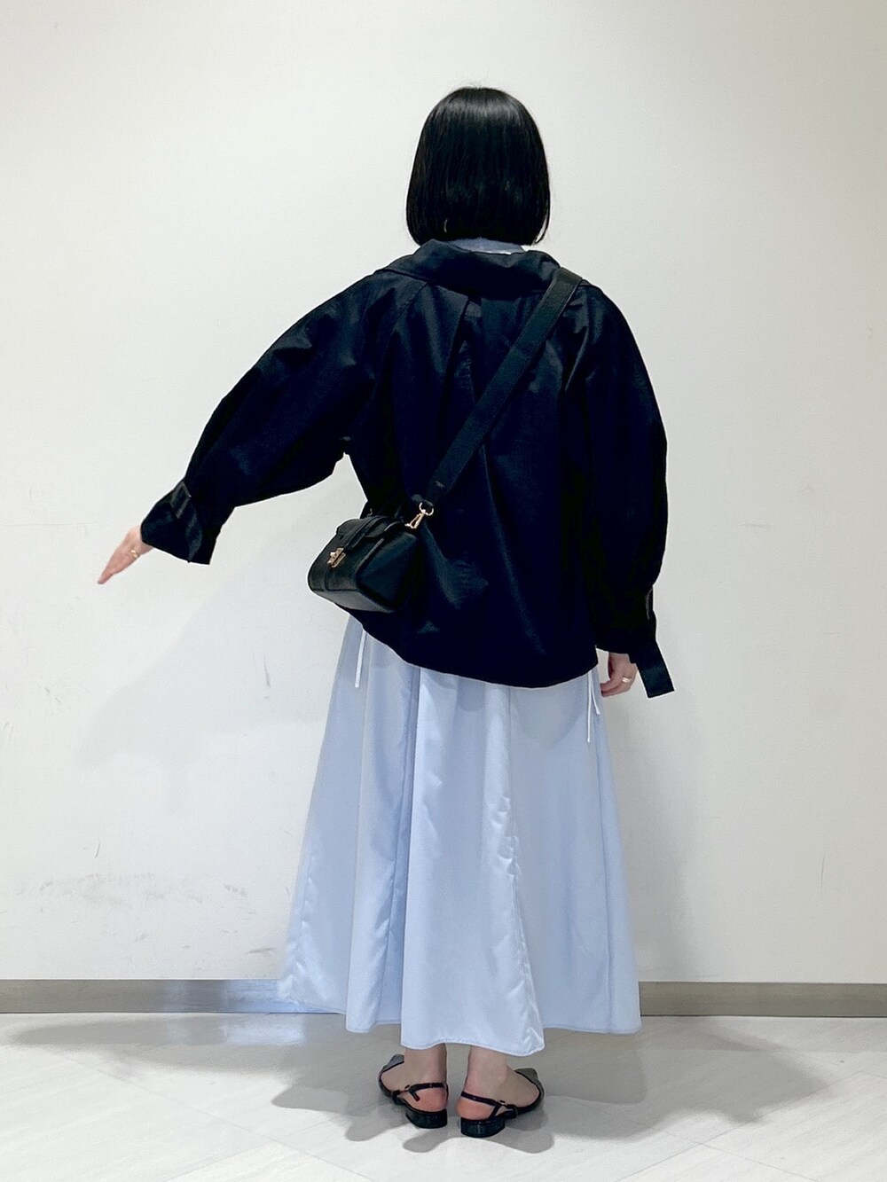 ブルー系のシャツワンピース、ブラック系のパンプス、ブラック系のショルダーバッグを着用したレディースの春コーディネートの3枚目の写真