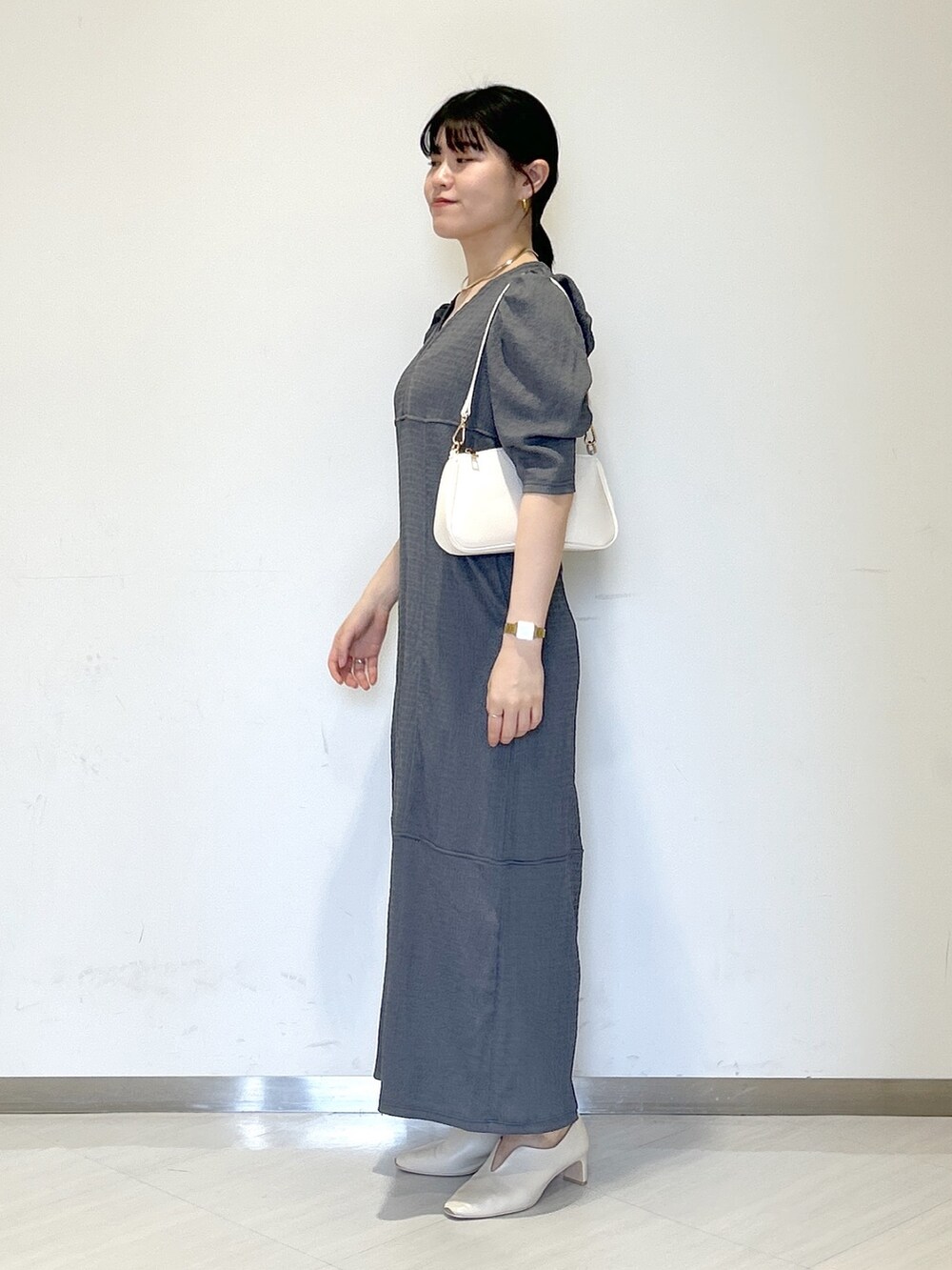 ベージュ系のパンプス、ホワイト系のショルダーバッグ、グレー系のワンピースを着用したレディースの夏コーディネートの2枚目の写真