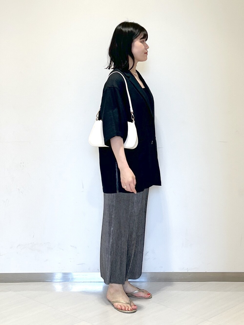 ブラック系のタンクトップ、ホワイト系のショルダーバッグ、ブラック系のテーラードジャケットを着用したレディースの夏コーディネートの4枚目の写真