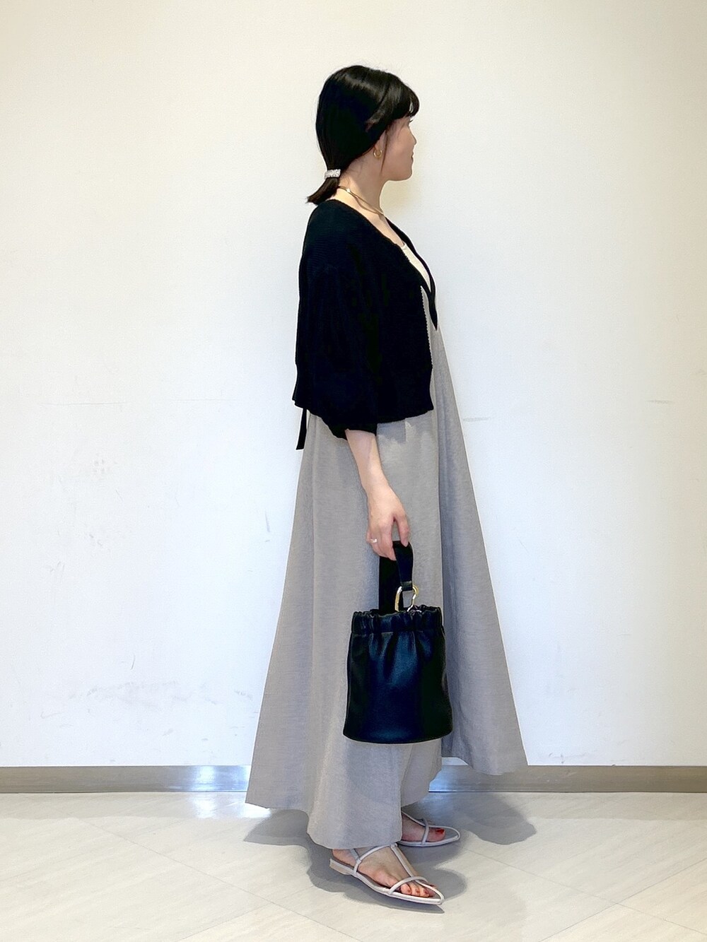 グレー系のジャンパースカート、ブラック系のカーディガン/ボレロ、ベージュ系のタンクトップを着用したレディースの夏コーディネートの5枚目の写真