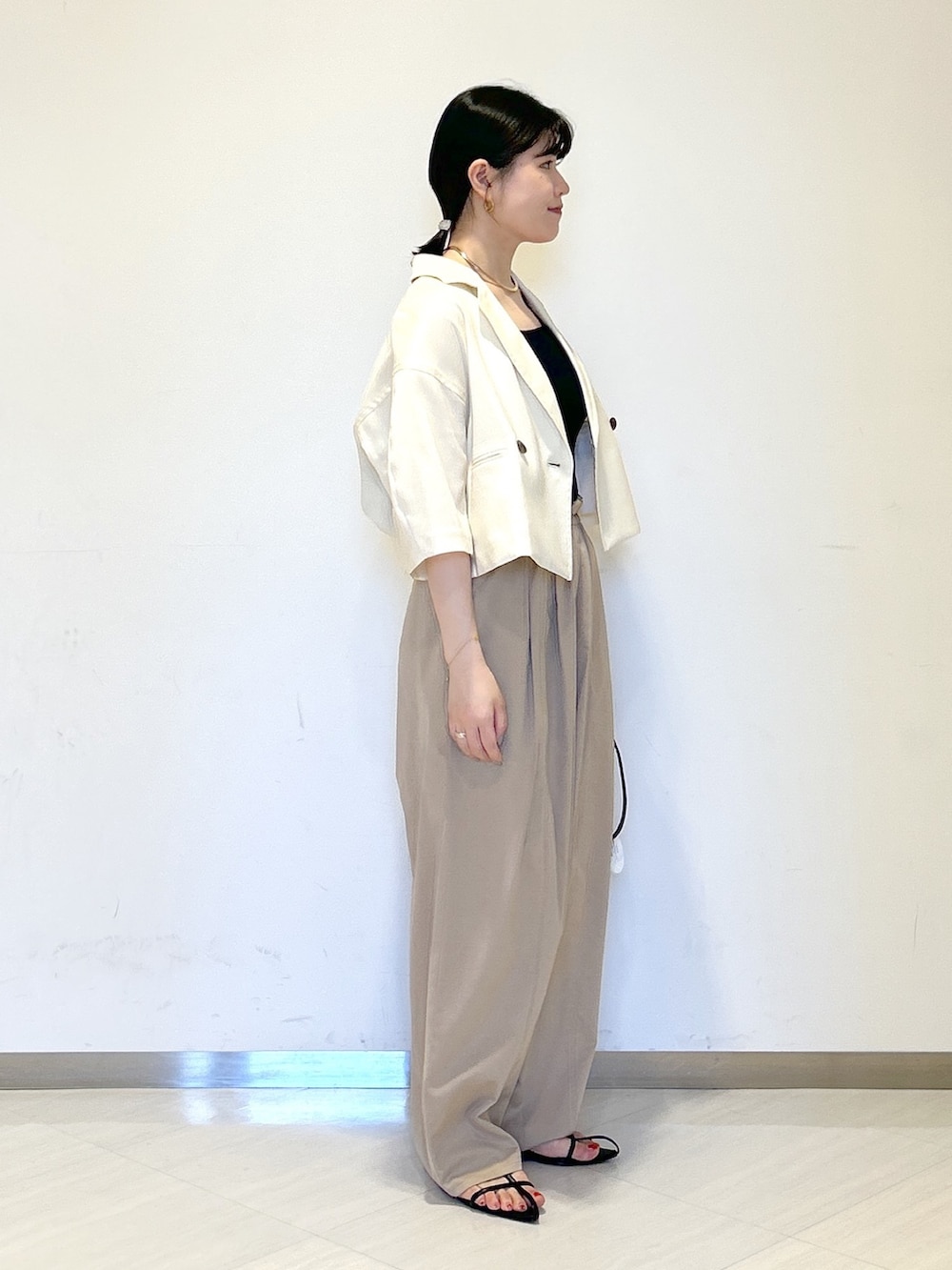 ブラック系のタンクトップ、ホワイト系のテーラードジャケット、イエロー系のその他パンツを着用したレディースの夏コーディネートの2枚目の写真