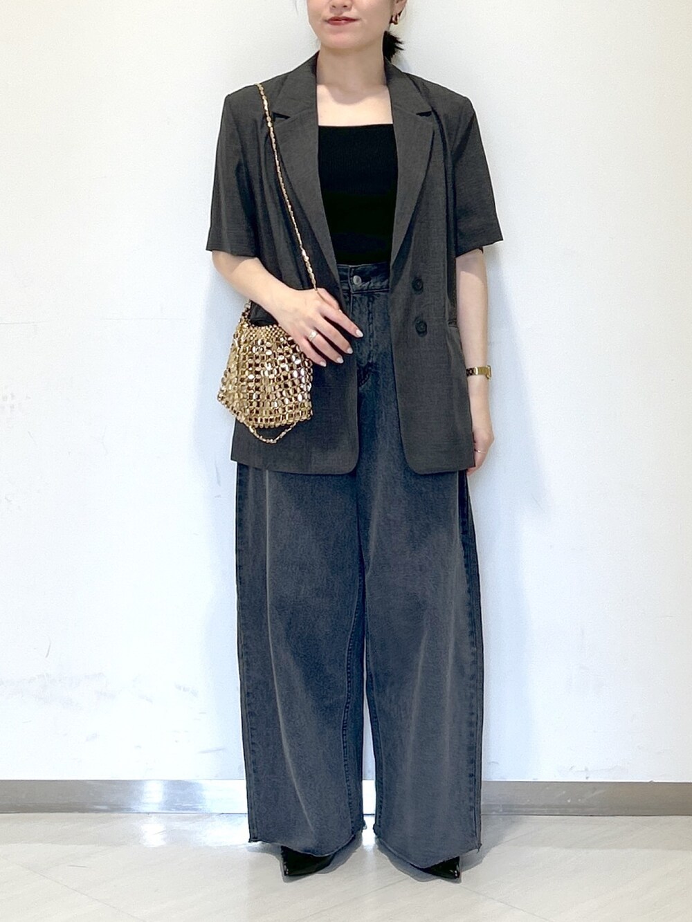 ゴールド系のショルダーバッグ、グレー系のテーラードジャケット、ブラック系のタンクトップを着用したレディースの夏コーディネートの2枚目の写真