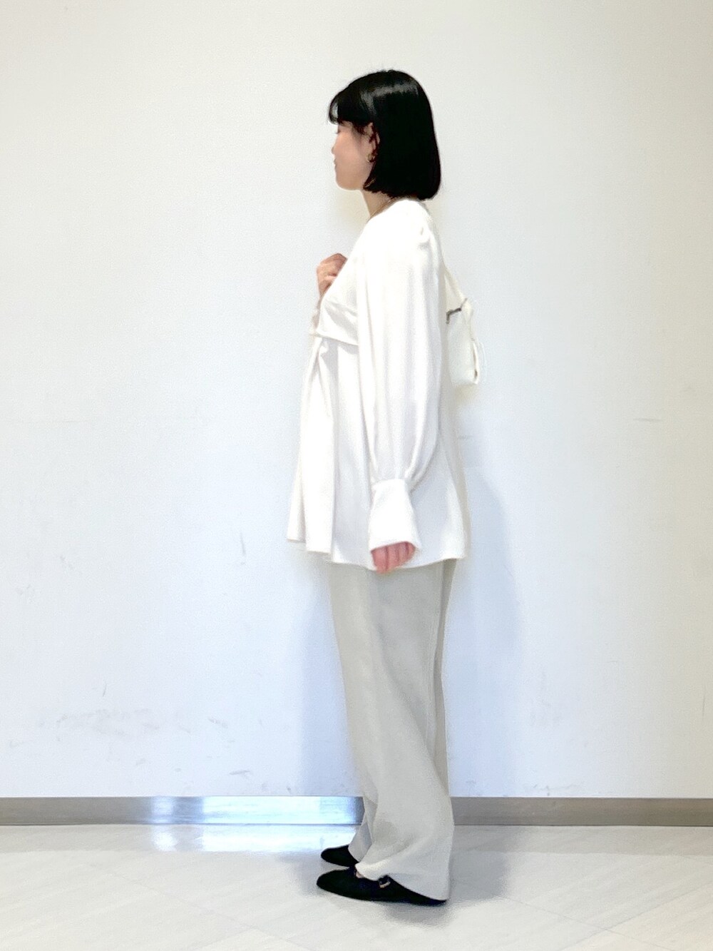 ホワイト系のシャツ/ブラウス、ホワイト系のショルダーバッグ、ベージュ系のスラックスを着用したレディースの春コーディネートの2枚目の写真