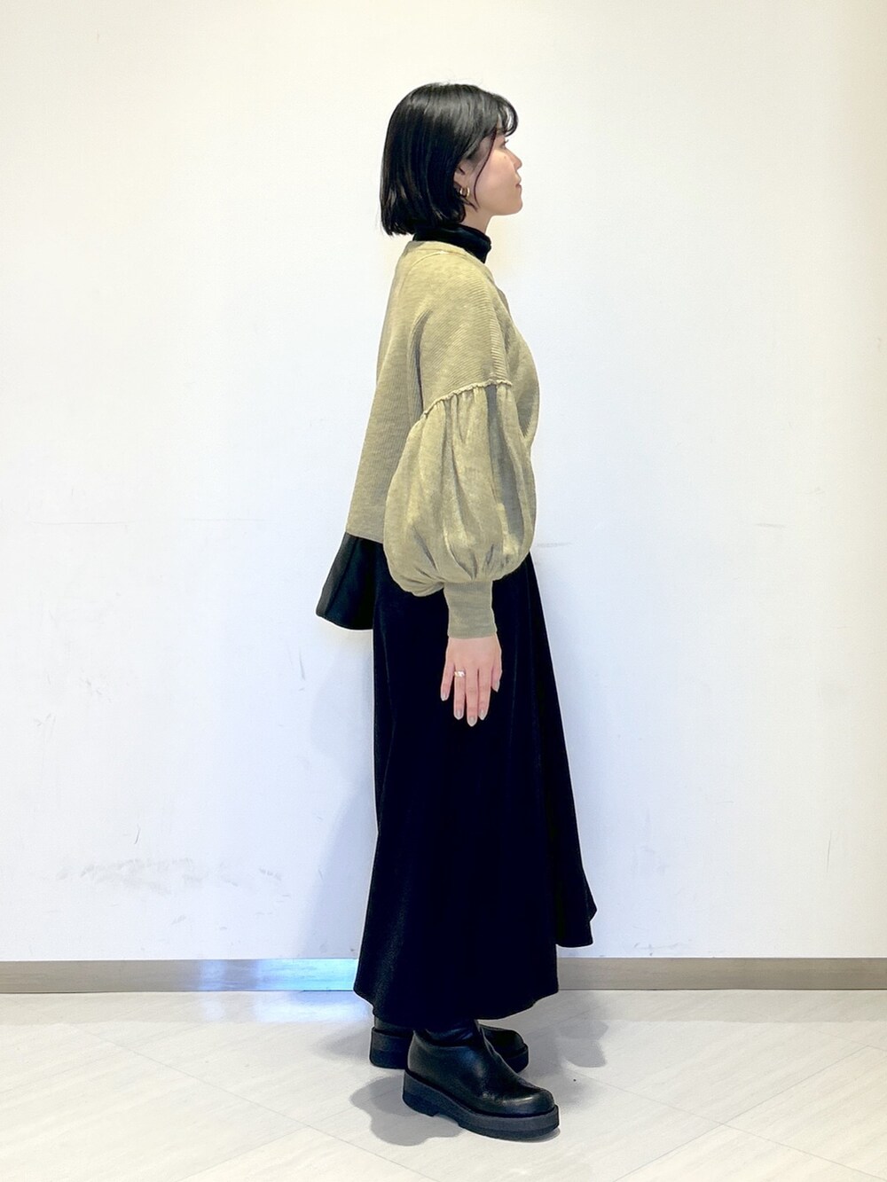 ホワイト系のワンピース、ブラック系のショルダーバッグ、グリーン系のカーディガン/ボレロを着用したレディースの冬コーディネートの4枚目の写真