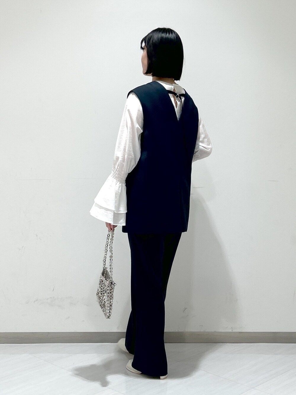 ホワイト系のシャツ/ブラウス、ブルー系のパンツドレス、シルバー系のショルダーバッグを着用したレディースの冬コーディネートの2枚目の写真