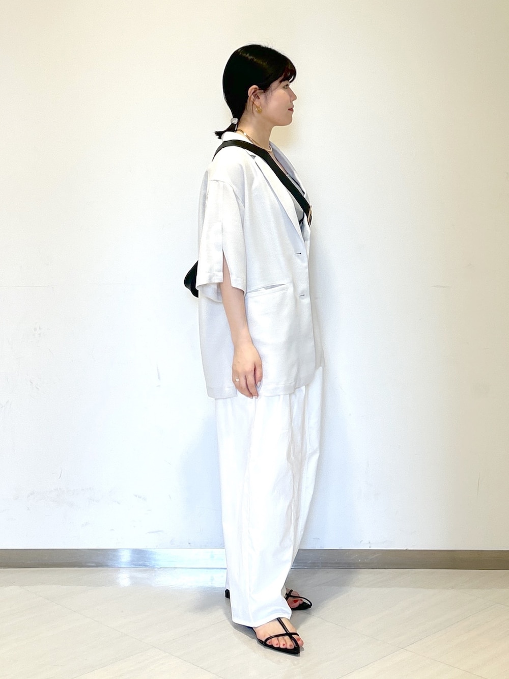 グレー系のタンクトップ、ブラック系のショルダーバッグ、グレー系のテーラードジャケットを着用したレディースの夏コーディネートの5枚目の写真