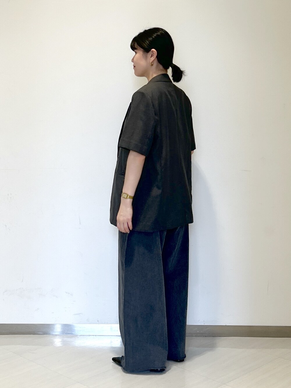 ゴールド系のショルダーバッグ、グレー系のテーラードジャケット、ブラック系のタンクトップを着用したレディースの夏コーディネートの3枚目の写真