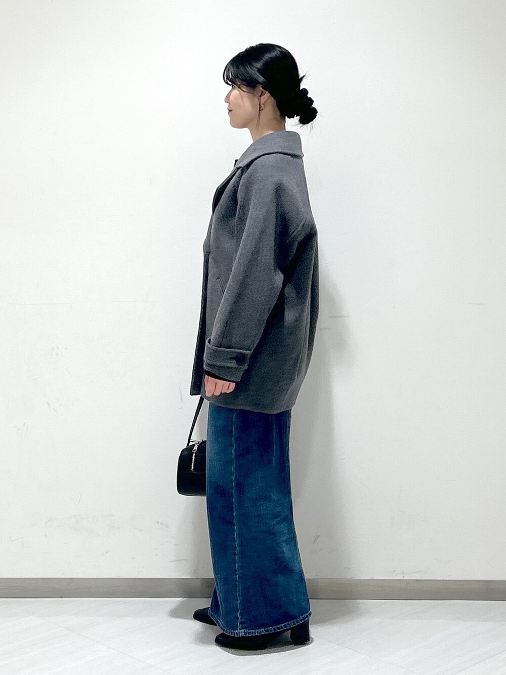 ブルー系のニット/セーター、グレー系のピーコート、ブルー系のデニムスカートを着用したレディースの冬コーディネートの2枚目の写真