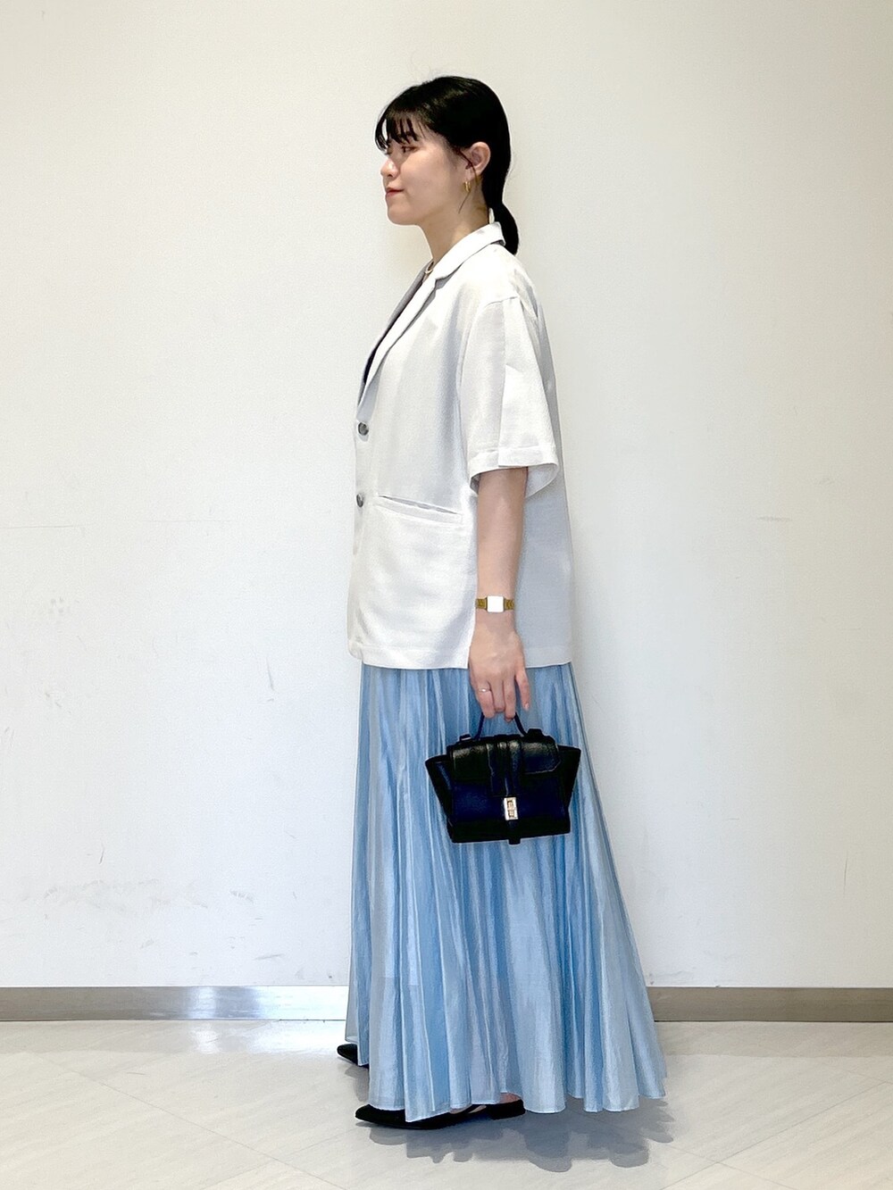 グレー系のテーラードジャケット、ブラック系のタンクトップ、ブラック系のショルダーバッグを着用したレディースの夏コーディネートの3枚目の写真