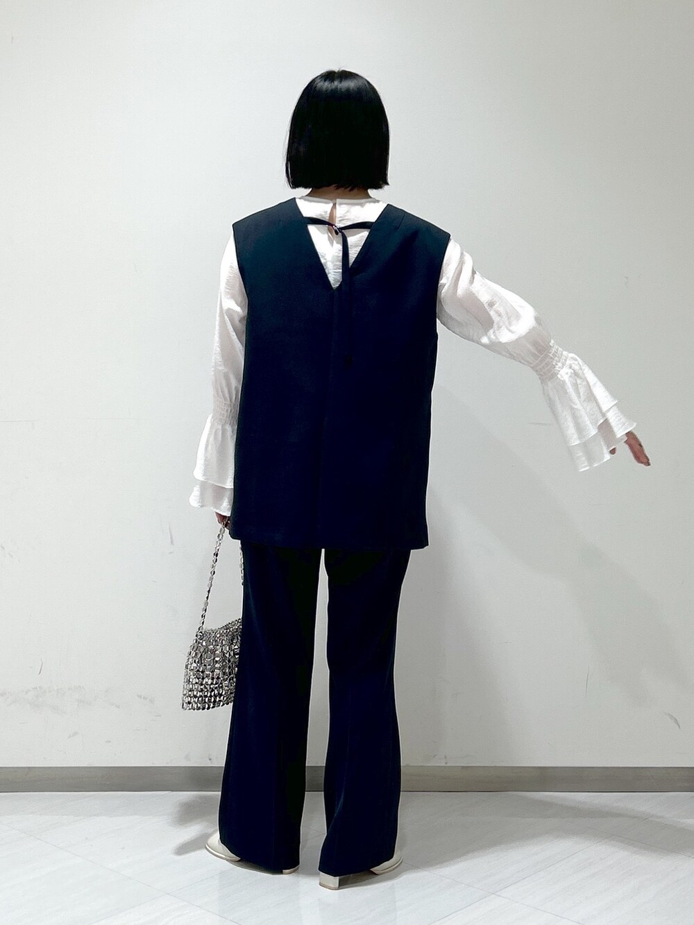 ホワイト系のシャツ/ブラウス、ブルー系のパンツドレス、シルバー系のショルダーバッグを着用したレディースの冬コーディネートの3枚目の写真