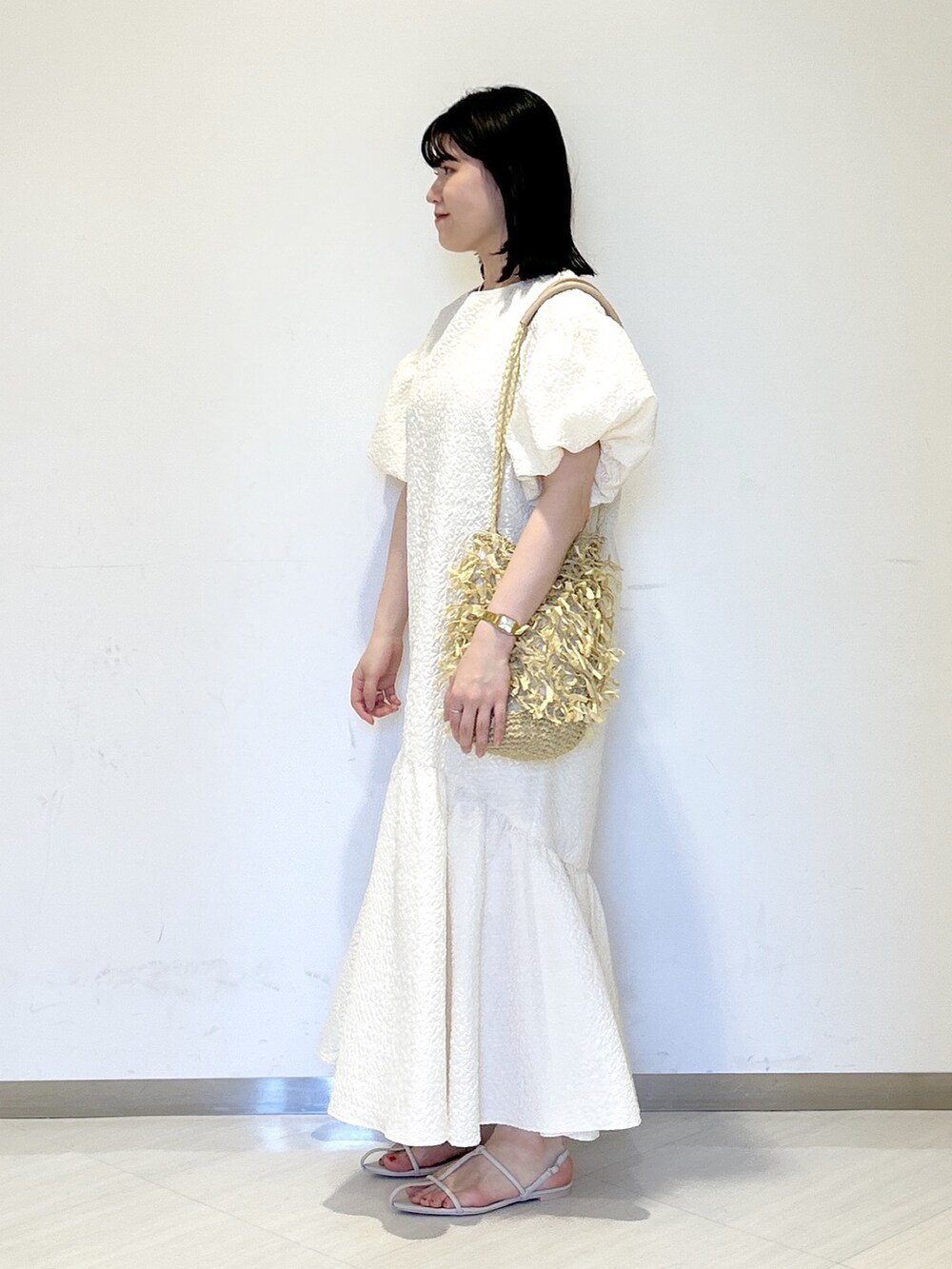 ホワイト系のワンピース、ホワイト系のサンダル、ベージュ系のトートバッグを着用したレディースの夏コーディネートの3枚目の写真