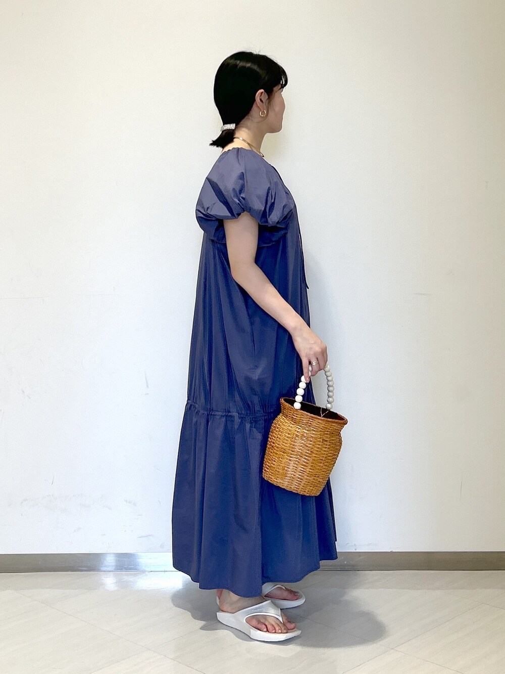 ブラウン系のかごバッグ、ホワイト系のサンダル、ブルー系のワンピースを着用したレディースの夏コーディネートの5枚目の写真