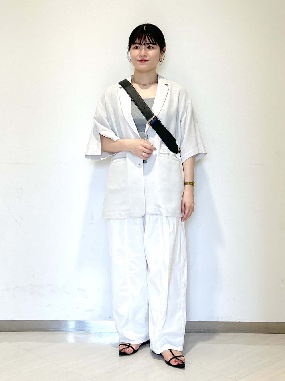 グレー系のタンクトップ、ブラック系のショルダーバッグ、グレー系のテーラードジャケットを着用したレディースの夏コーディネートの6枚目の写真